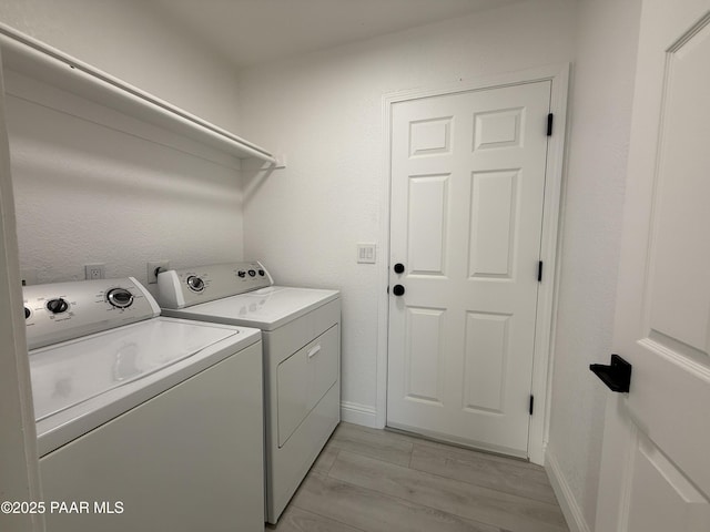 clothes washing area featuring light wood-type flooring, baseboards, laundry area, and washing machine and clothes dryer