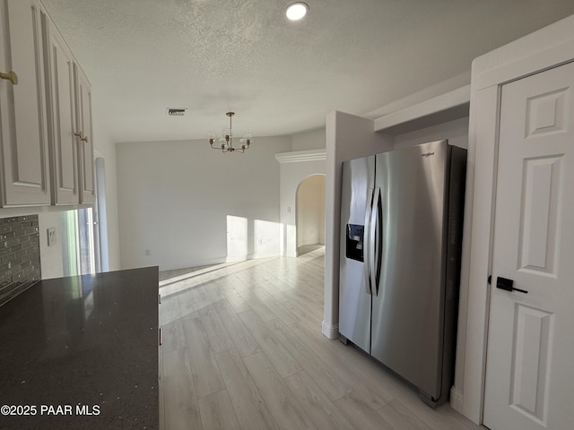 kitchen featuring visible vents, a chandelier, light wood-type flooring, stainless steel refrigerator with ice dispenser, and a textured ceiling