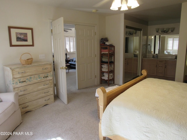 bedroom featuring ceiling fan, light colored carpet, and ensuite bath