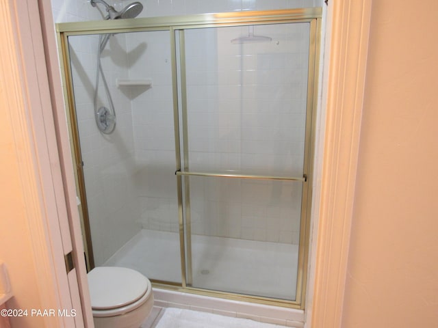 bathroom featuring toilet and a shower with door