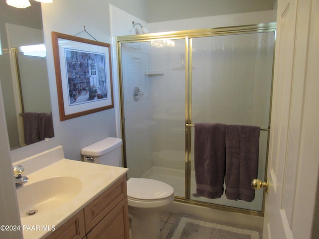 bathroom featuring tile patterned flooring, a shower with door, vanity, and toilet