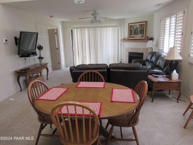 carpeted dining room with a fireplace and ceiling fan