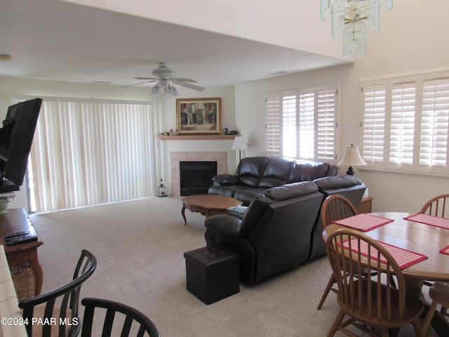 living room with a fireplace, carpet, and ceiling fan with notable chandelier