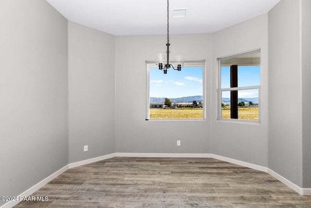 empty room featuring hardwood / wood-style flooring, a mountain view, and an inviting chandelier