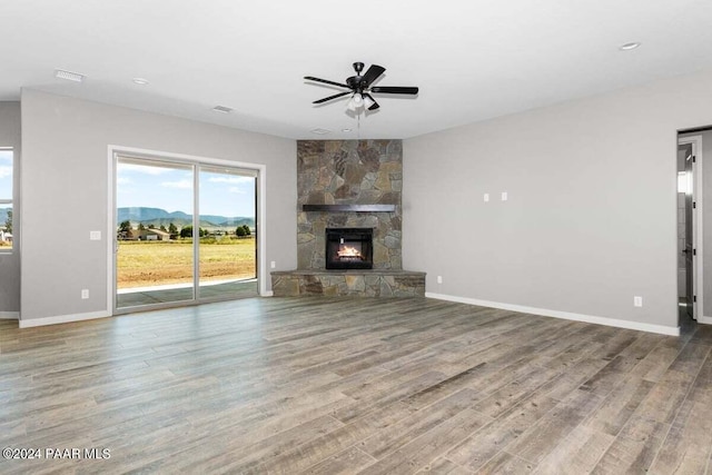 unfurnished living room featuring hardwood / wood-style flooring, a mountain view, ceiling fan, and a fireplace