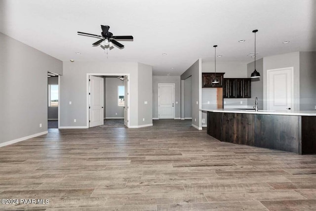 kitchen with dark brown cabinetry, ceiling fan, sink, hardwood / wood-style floors, and decorative light fixtures