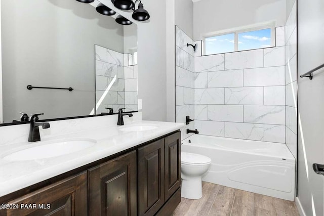 full bathroom with vanity, toilet, wood-type flooring, and tiled shower / bath