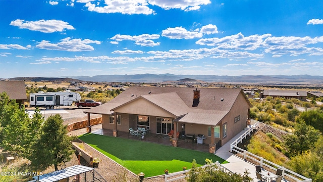 rear view of property featuring a mountain view and a lawn