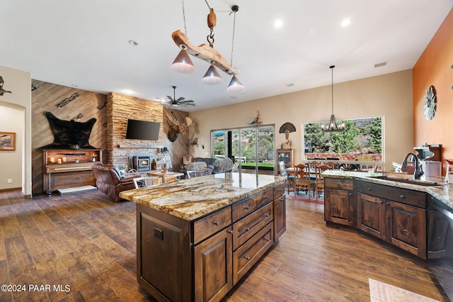 kitchen featuring dishwasher, a kitchen island, light stone counters, and dark wood-type flooring