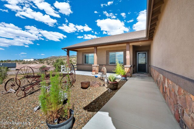 9757 N Heartland Dr, Prescott Valley, AZ 86315 - view of exterior entry featuring stucco siding, a patio area, and a mountain view