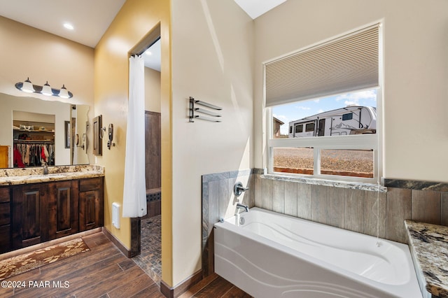 bathroom featuring vanity, wood-type flooring, and a tub to relax in