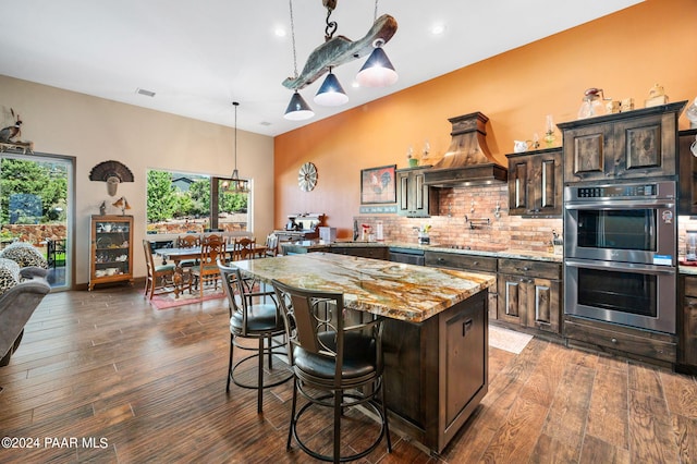 kitchen with appliances with stainless steel finishes, a center island, dark brown cabinets, and dark wood-type flooring