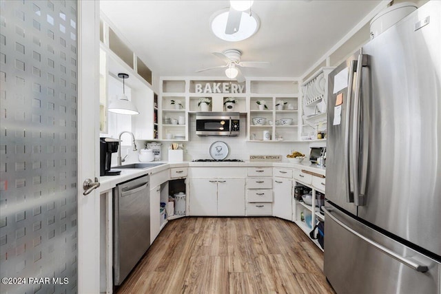 kitchen featuring stainless steel appliances, sink, pendant lighting, white cabinets, and light hardwood / wood-style floors