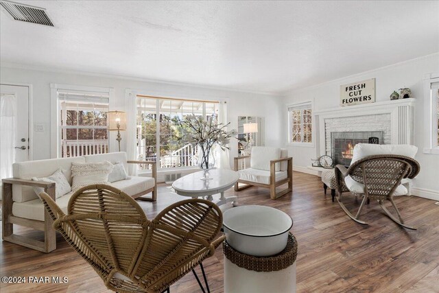 living room featuring crown molding, wood-type flooring, and a brick fireplace