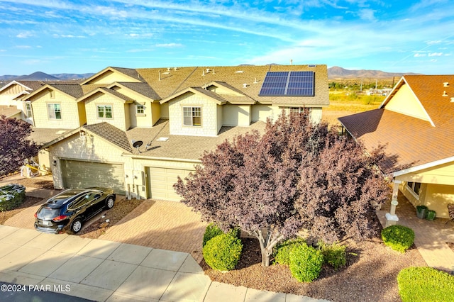 view of front of house with solar panels, a garage, and a mountain view