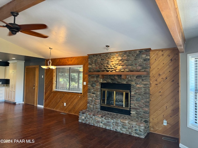 unfurnished living room with lofted ceiling with beams, wood walls, visible vents, and a stone fireplace