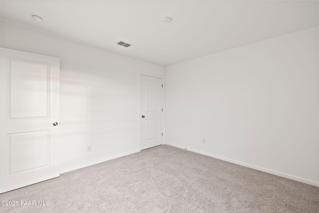 empty room with carpet floors, visible vents, and baseboards