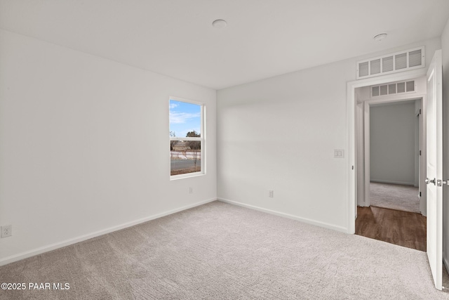 empty room with carpet, visible vents, and baseboards