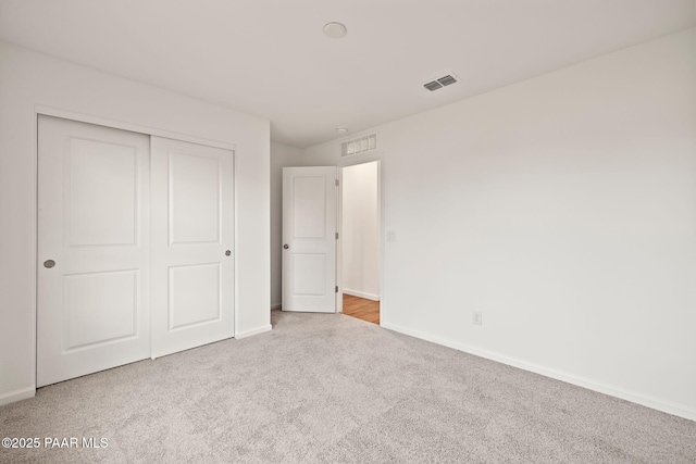 unfurnished bedroom featuring carpet, a closet, visible vents, and baseboards