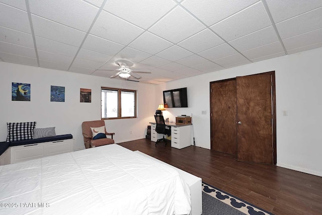 bedroom featuring baseboards, a paneled ceiling, a ceiling fan, and dark wood-style flooring