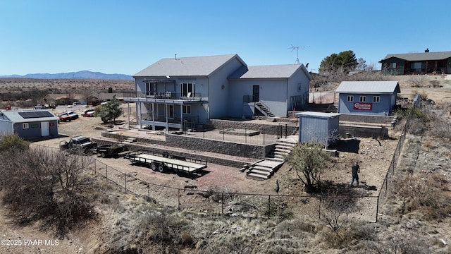 rear view of property featuring stairway, a mountain view, and fence