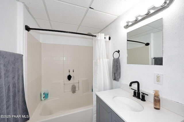 full bathroom featuring a drop ceiling, shower / bath combo with shower curtain, and vanity