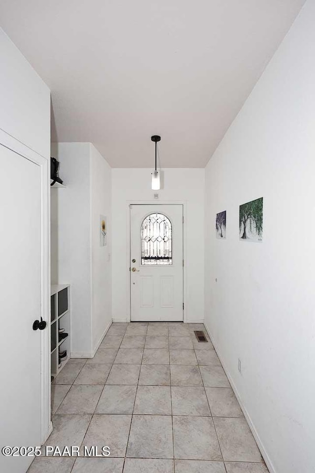 doorway to outside with light tile patterned floors, visible vents, and baseboards