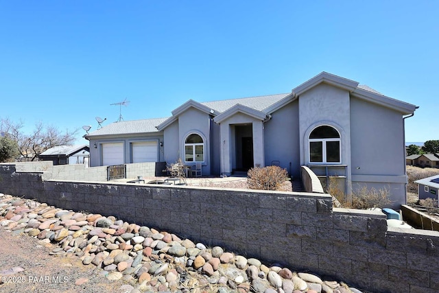 ranch-style home featuring stucco siding, an attached garage, and fence