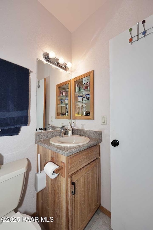 half bath with tile patterned floors, toilet, and vanity