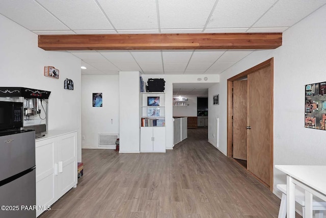 kitchen with visible vents, freestanding refrigerator, white cabinets, black microwave, and light wood finished floors