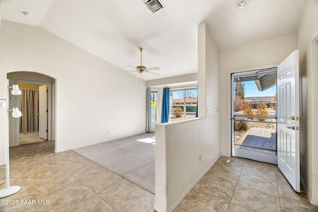 foyer featuring arched walkways, light tile patterned floors, light carpet, visible vents, and vaulted ceiling