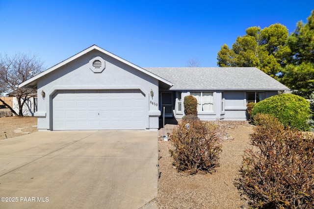 ranch-style house featuring driveway, a shingled roof, an attached garage, and stucco siding