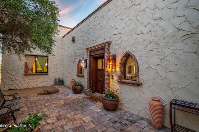 exterior entry at dusk featuring a patio area