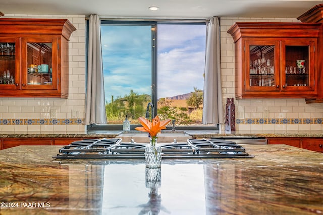 kitchen with tasteful backsplash, stone countertops, and stainless steel gas stovetop