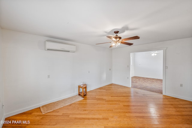 empty room with a wall mounted air conditioner, light hardwood / wood-style flooring, and ceiling fan