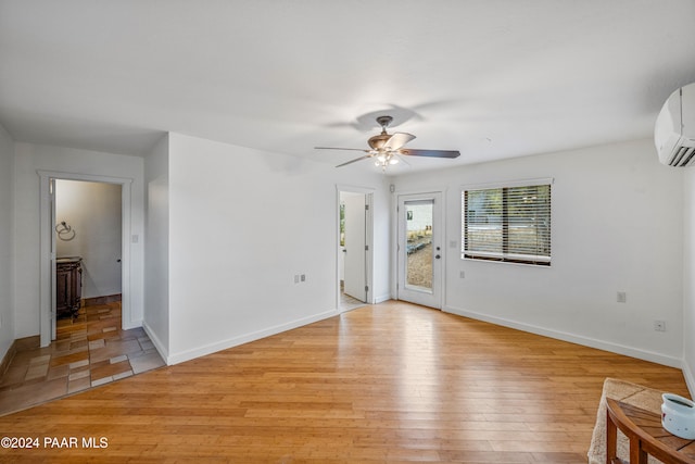 unfurnished room featuring a wall mounted air conditioner, light hardwood / wood-style flooring, and ceiling fan