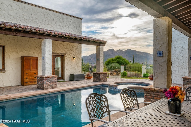 view of pool with a patio area, an in ground hot tub, and a mountain view