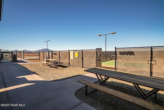 view of jungle gym featuring a tennis court and fence