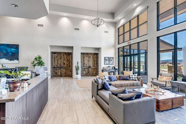 living room with visible vents, a notable chandelier, and light wood finished floors