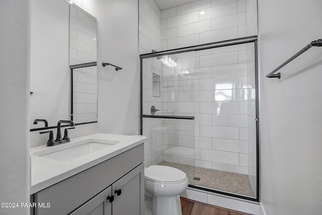 bathroom with hardwood / wood-style flooring, vanity, walk in shower, and toilet