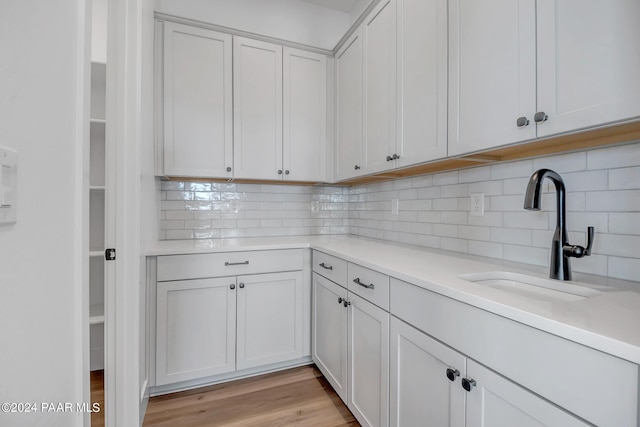 kitchen with light countertops, tasteful backsplash, a sink, and white cabinetry