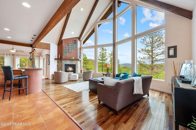 living room with baseboards, a tile fireplace, high vaulted ceiling, and beamed ceiling