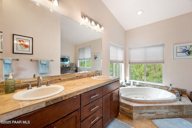 full bathroom with double vanity, a whirlpool tub, a sink, and lofted ceiling