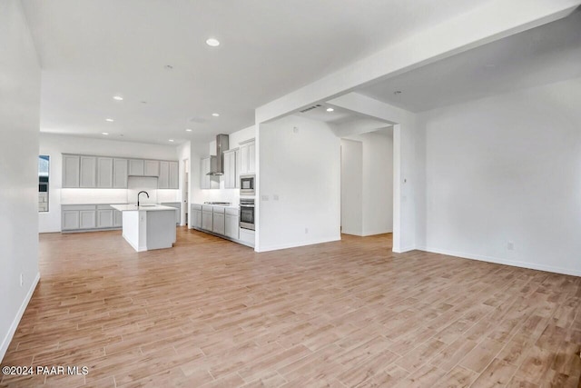 unfurnished living room with light hardwood / wood-style floors and sink