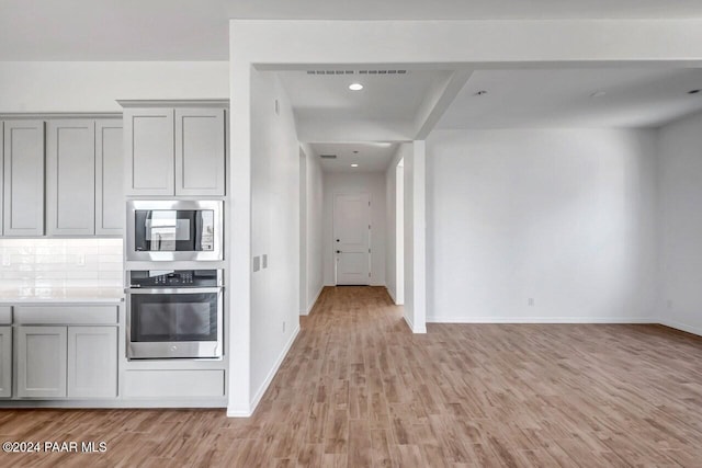 kitchen featuring tasteful backsplash, gray cabinets, light hardwood / wood-style flooring, and stainless steel appliances