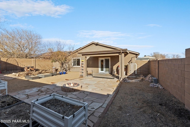 back of house featuring water heater, a patio area, and a fire pit