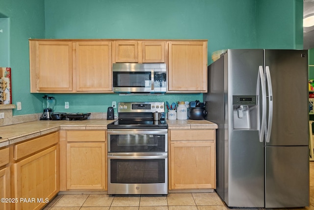 kitchen featuring tile counters, light brown cabinets, and appliances with stainless steel finishes