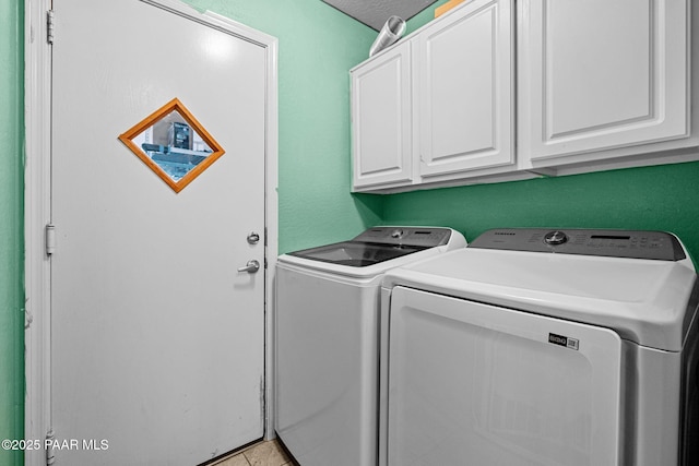 laundry room featuring cabinets, light tile patterned floors, washer and dryer, and a textured ceiling