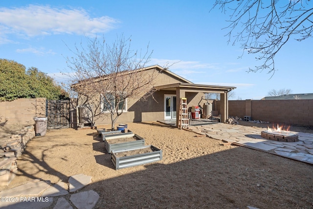 back of property with an outdoor fire pit and a patio area