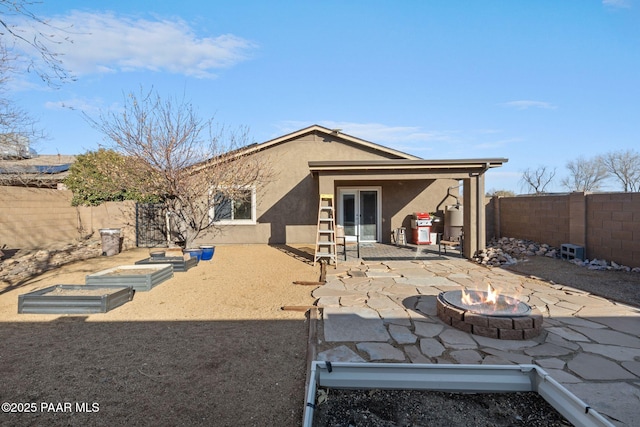 rear view of property featuring a patio area and a fire pit